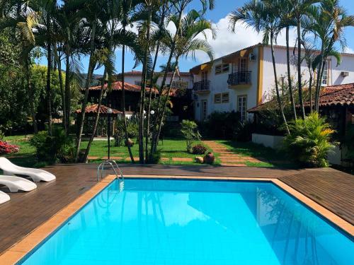 a swimming pool in front of a house with palm trees at Pousada Villa Real in Tiradentes