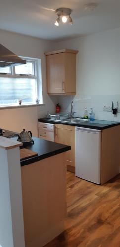 a kitchen with wooden cabinets and a black counter top at Ballycastle Town Centre Apartment in Ballycastle