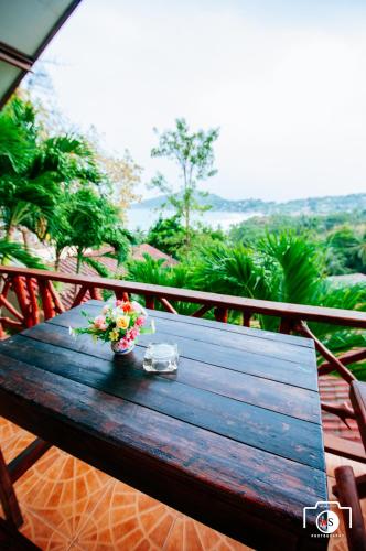 a wooden table with a bowl of flowers on a balcony at Venus Resort in Haad Rin