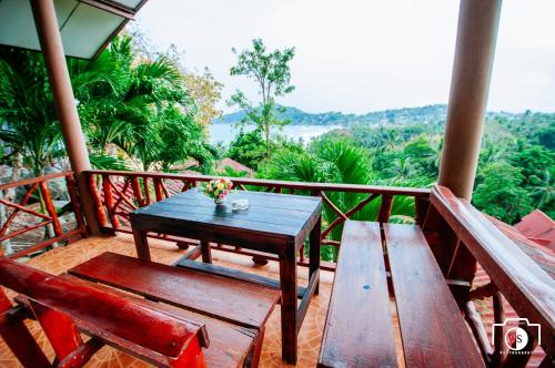 a wooden table and chairs on a balcony with a view at Venus Resort in Haad Rin