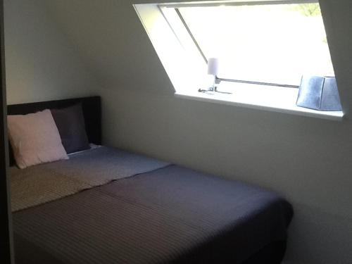 Dormitorio pequeño con cama y ventana en Appartement in der Waldsiedlung, en Leverkusen