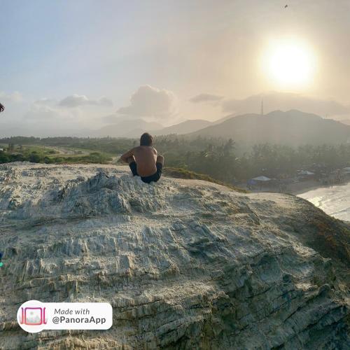 a man sitting on a rock looking at the sun at Cimarron Suites Playa Parguito in Aricagua