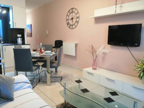 a living room with a table and a clock on the wall at Seabreeze Apartment in St Paul's Bay