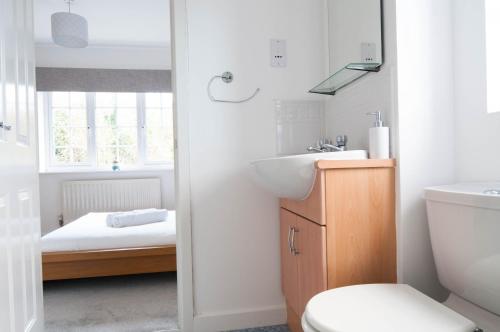 a bathroom with a sink and a toilet and a bed at The Dakota - next to East Midlands Airport in Castle Donington