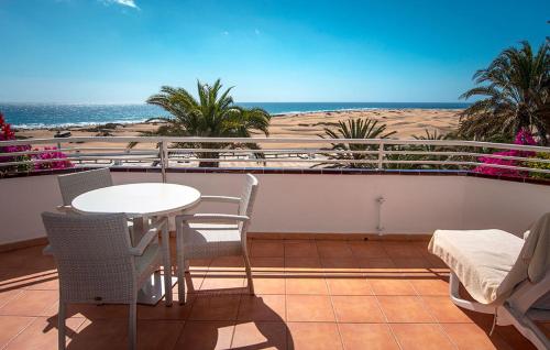 
a beach area with chairs, tables, and a balcony at Taboga - Adults Only in Playa del Ingles
