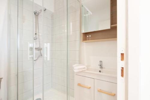 ein weißes Bad mit einer Dusche und einem Waschbecken in der Unterkunft Studio Vahiny1 All comfort WIFI NETFLIX Parking in Saint-Nazaire