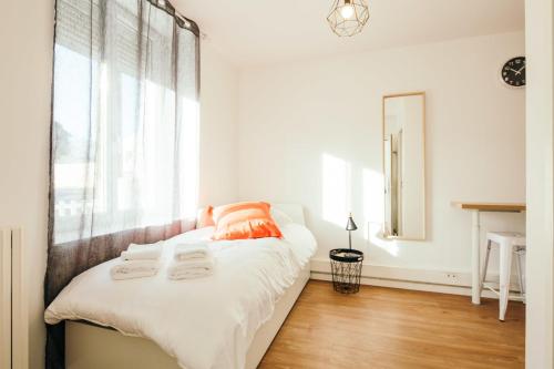 una camera da letto con un letto con lenzuola bianche e un cuscino arancione di Studio Vahiny1 All comfort WIFI NETFLIX Parking a Saint-Nazaire