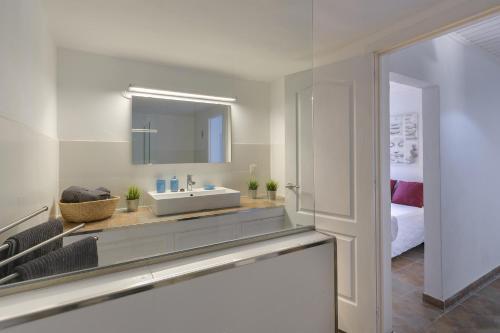 a white bathroom with a sink and a bed at Casa Amanecer in Tías