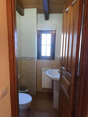 een badkamer met een wastafel, een toilet en een raam bij El Pajar in San Ciprián
