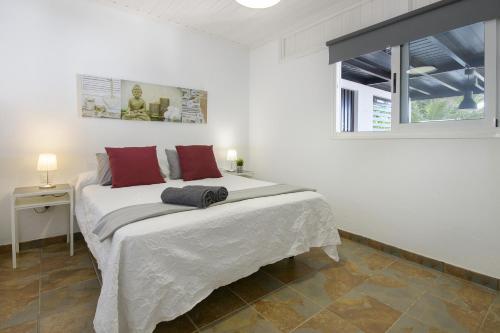 a white bedroom with a large bed with red pillows at Casa Amanecer in Tías