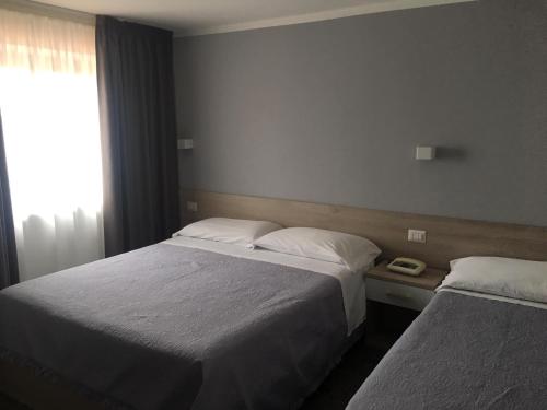 a hotel room with two beds and a window at Piccolo Hotel Lamezia in SantʼEufemia Lamezia