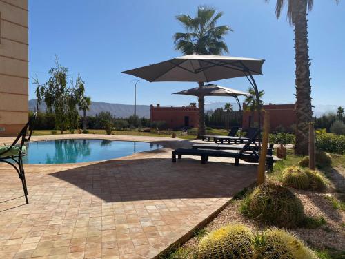 a picnic table with an umbrella next to a pool at Villa Diaf Johanne in Aït Ourir