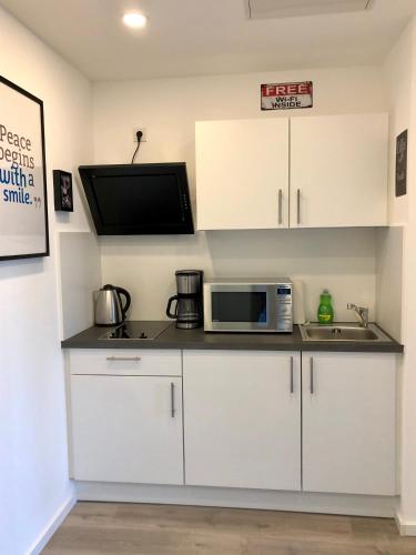 a kitchen with white cabinets and a microwave at Deluxe Apartments Messe Flughafen in Leinfelden-Echterdingen