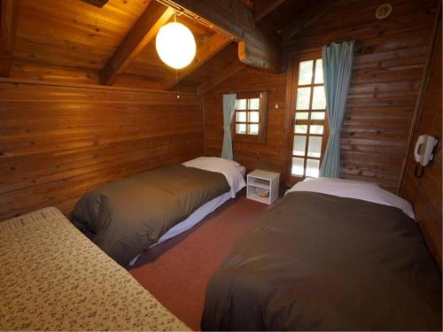 a bedroom with two beds in a log cabin at ペンション イメージハウス in Hara