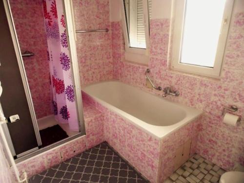 La salle de bains rose est pourvue d'une baignoire et d'une douche. dans l'établissement Ferienwohnung Hermann, à Spangenberg