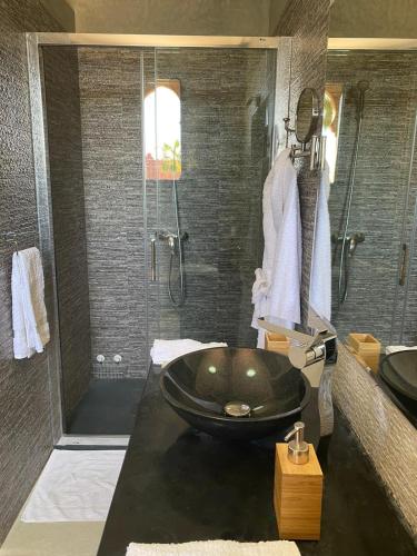 a bathroom with a black tub and a shower at Villa Diaf Johanne in Aït Ourir