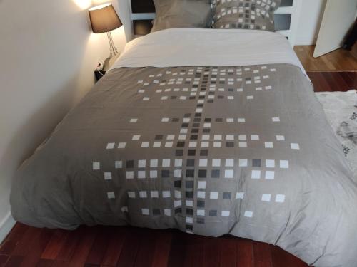 uma cama com um edredão castanho e branco em Appartement tout équipé au calme - RefKL em Montfermeil