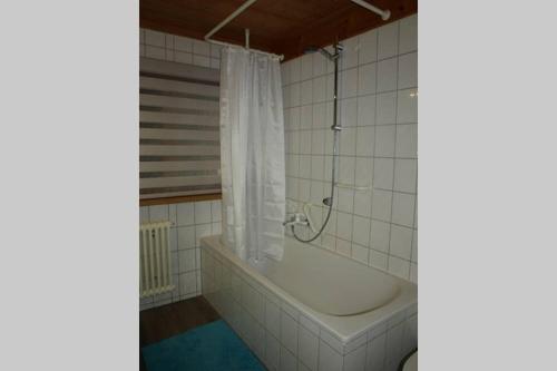 y baño blanco con bañera y ducha. en Großzügige Ferienwohnung am Kloster, en Kirchzarten