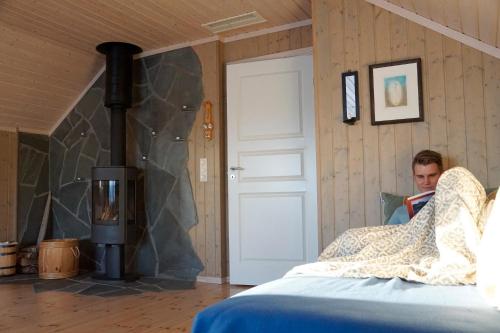 a person sitting in a bed reading a book at Nyken Resort - The apartment in Nyksund