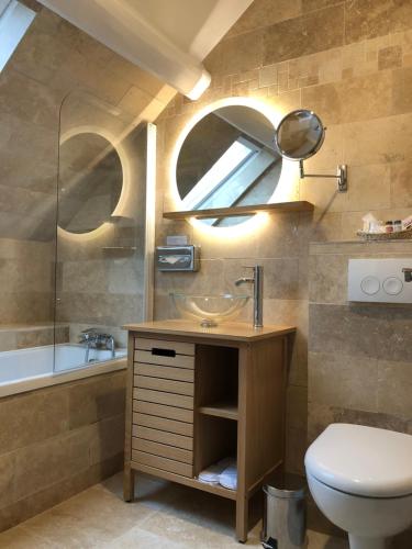 a bathroom with a sink and a toilet and a tub at Auberge du Manet in Montigny-le-Bretonneux