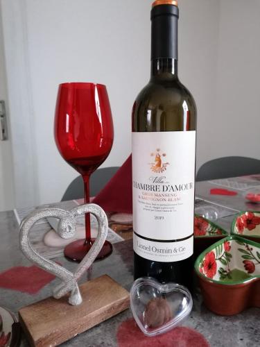 a bottle of red wine next to a glass at The Primevères Home - SPA in Sainte-Marie-aux-Mines