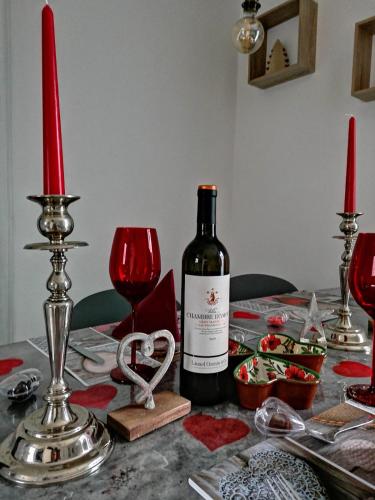 a bottle of wine sitting on a table with red candles at The Primevères Home - SPA in Sainte-Marie-aux-Mines