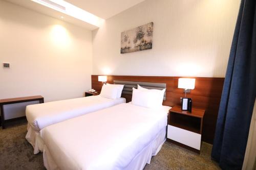 two beds in a hotel room with white sheets at Eva Hotel in Jeddah