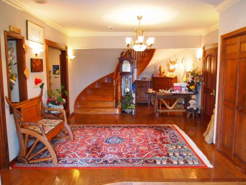 ein Wohnzimmer mit einer Treppe und einer Großvater-Uhr in der Unterkunft Petit Hotel Corinthian in Rebun