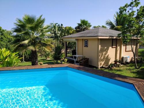 a villa with a swimming pool in front of a house at Villa & Bungalow Fleur de Coco in Sainte-Anne