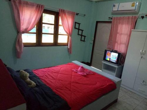 Un dormitorio con una cama roja con un osito de peluche. en Wangtong Resort 2 en Ban Huai Salok
