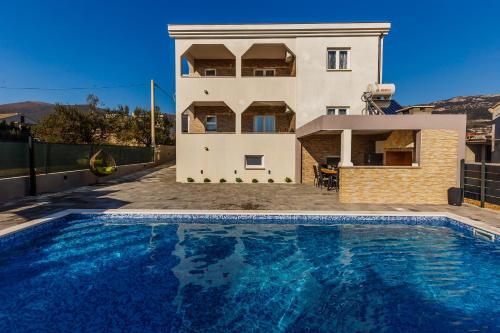 a house with a swimming pool in front of a house at VILLA LaMARIN in Kaštela
