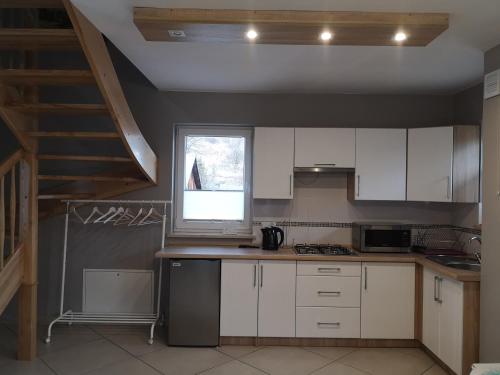 a kitchen with white cabinets and a window at Domek u Basi in Grywałd