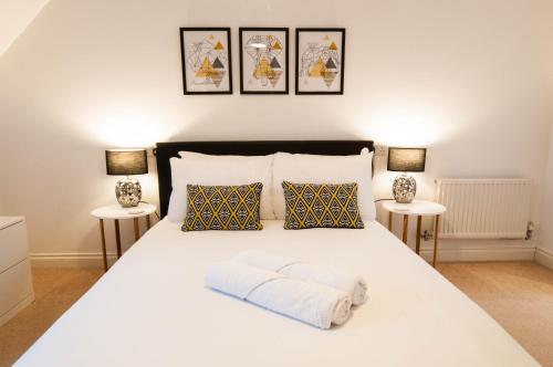 a bedroom with a white bed with three pictures on the wall at Atlas House - Ideal for Contractors or Derby County Fans in Derby