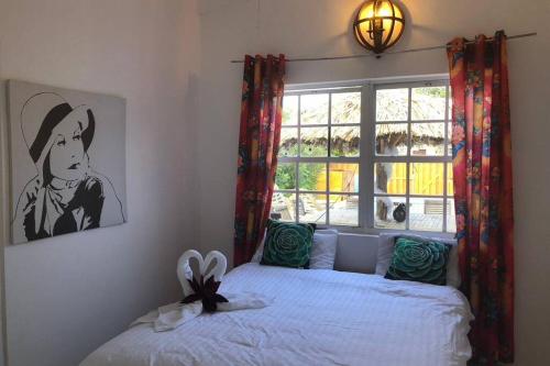 1 dormitorio con 1 cama con ventana y una foto en Private Home with Pool, Outdoor Kitchen and BBQ, en Kralendijk
