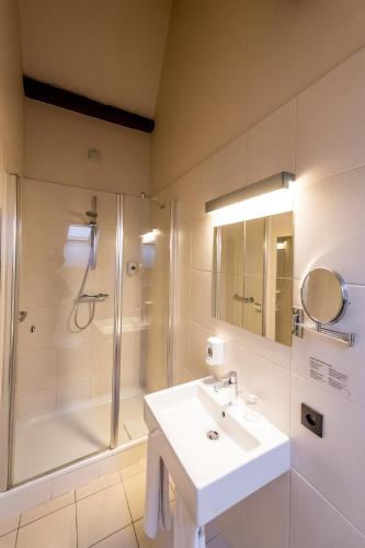 a white bathroom with a sink and a shower at Hotel Onderbergen in Ghent