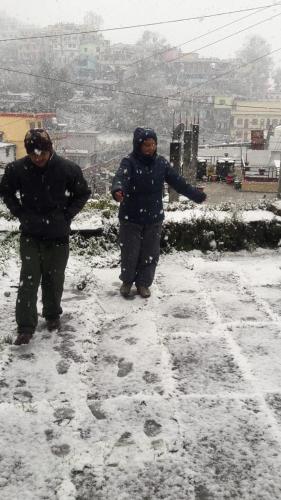 two people walking down a snow covered street at Hotel Milam Inn in Almora