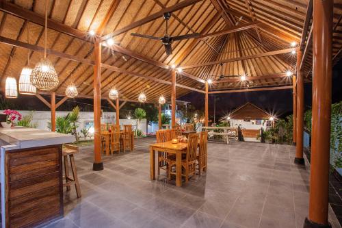 a pavilion with wooden tables and chairs and lights at D'Coin Lembongan in Nusa Lembongan