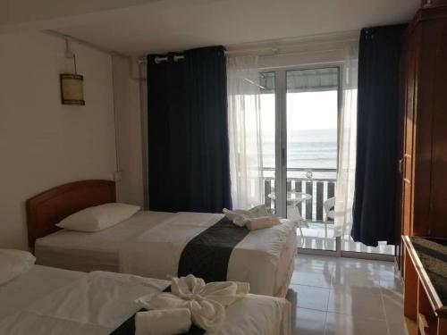 two beds in a room with a view of the ocean at Perhentian Chomel Chalet in Perhentian Island