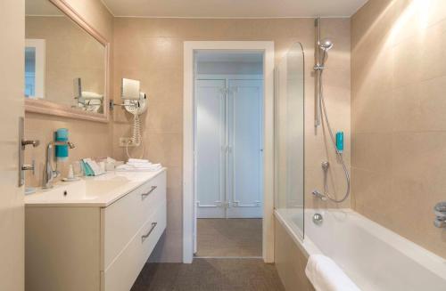a bathroom with a shower and a sink and a tub at Hotel Lugano in Knokke-Heist