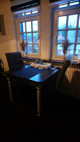 een donkere kamer met een tafel, een stoel en ramen bij Bed und Breakfast "Die Perle von Gronau" in Gronau