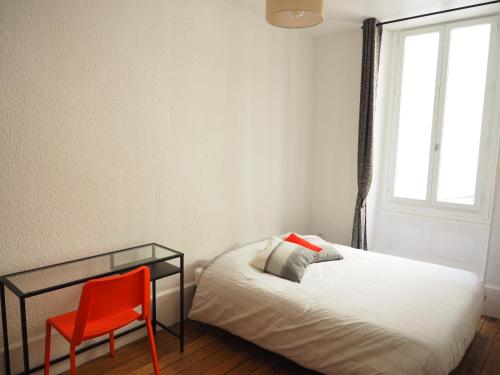 una camera con letto e sedia rossa di Appartement le st jean - centre historique a Valence