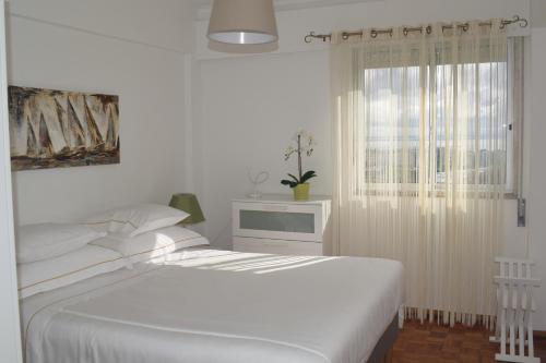 a white bedroom with a bed and a window at Vistas Sobre O Rio Tejo in Lisbon