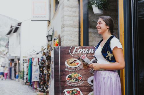 a woman standing next to a sign on a street at Hotel Emen in Mostar