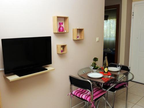 a dining room with a table and a television on a wall at Sunny Family Apartment in Iraklitsa