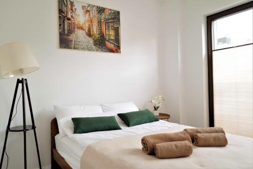1 dormitorio con cama blanca y almohadas verdes en Central Port Warsaw Apartment, en Varsovia