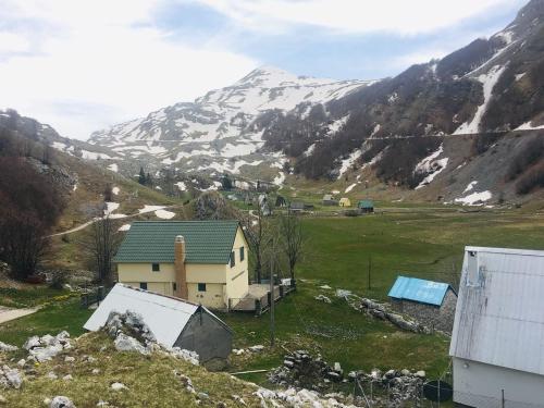 a house on a hill with a snow covered mountain at Katun Mokra accommodation & horseback riding in Podgorica