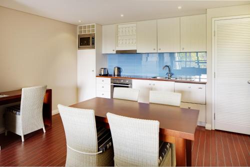 a kitchen with a wooden table and white cabinets at Seashells Yallingup in Yallingup