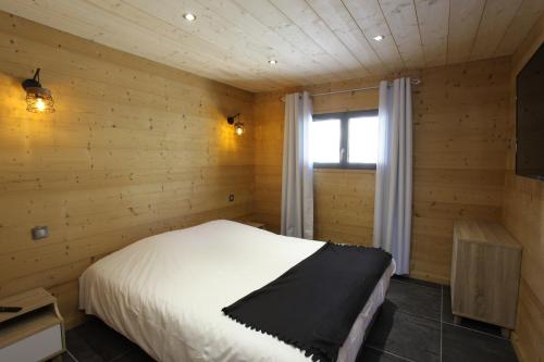 Un dormitorio con una cama en una pared de madera. en Bottières, en Saint-Pancrace