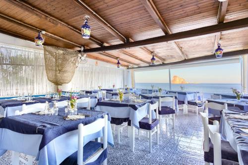 a restaurant with blue tables and white chairs and the ocean at Eunymos Panarea in Panarea