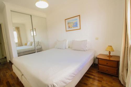 a bedroom with a large white bed and a mirror at Vau Costa beach apartment with pool in Alvor